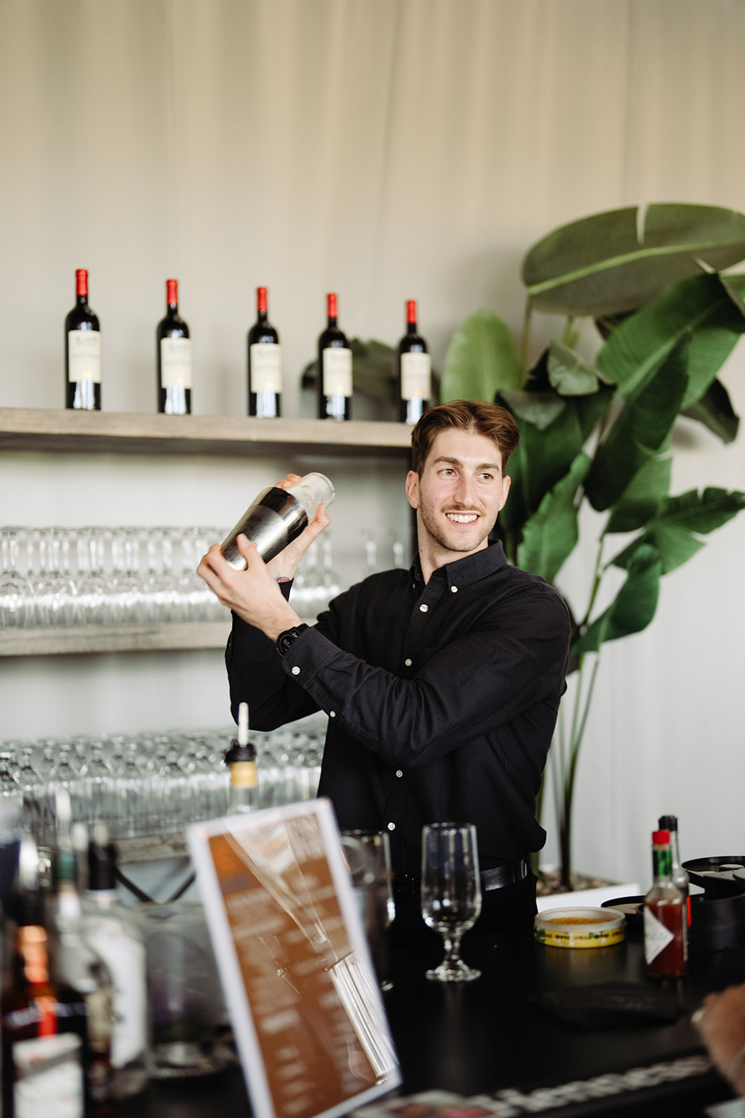 Un barman souriant mixe un verre à une réception de mariage, ajoutant une touche festive à la célébration.